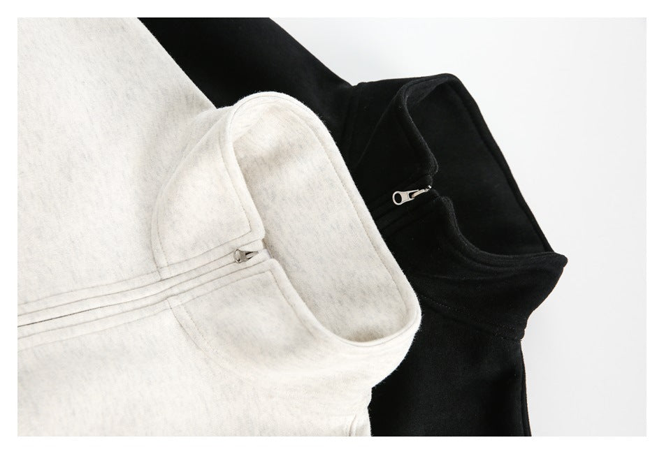 Close-up of the raised collars and quarter zippers on light heather and black sweatshirts.