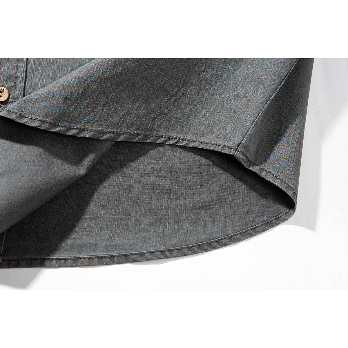 Close-up of the charcoal-gray shirt's curved hem, stitched seams, and short sleeve.
