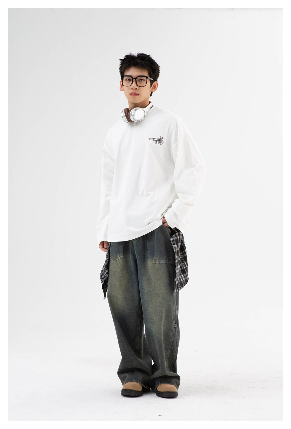 Full-length front view of a model wearing an oversized white long-sleeve shirt with a small chest graphic.