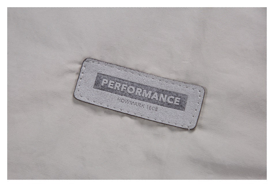 Close-up of a sewn light gray garment patch reading “PERFORMANCE” and “KOTMARK 1608.”