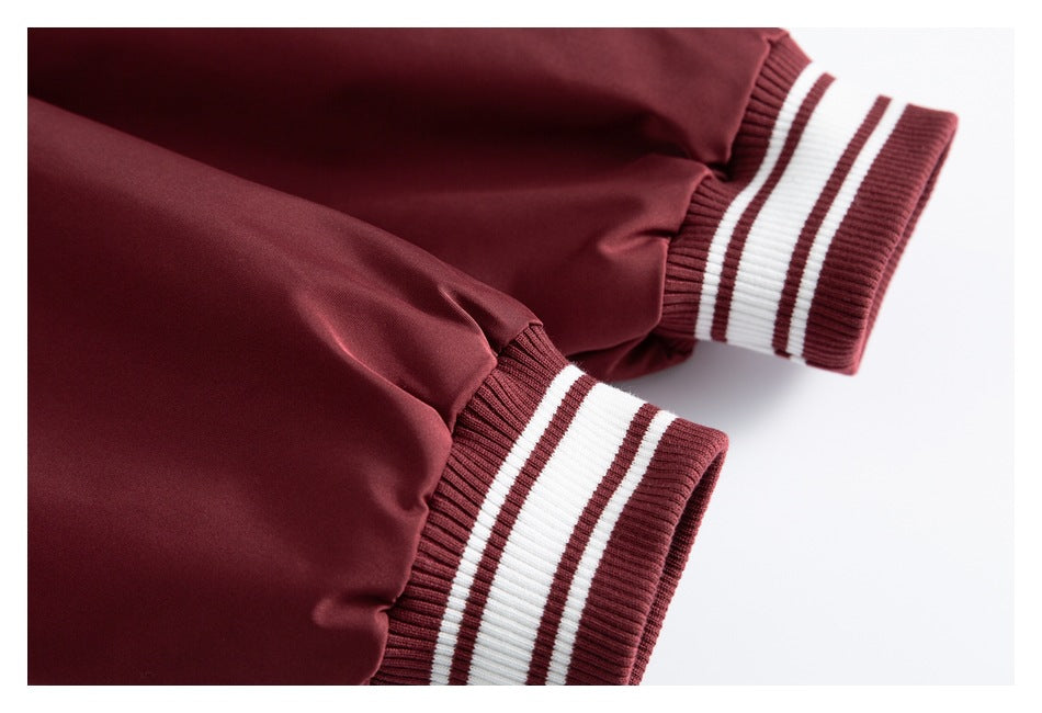 Close-up of two burgundy jacket sleeves with ribbed cuffs striped in burgundy and white.