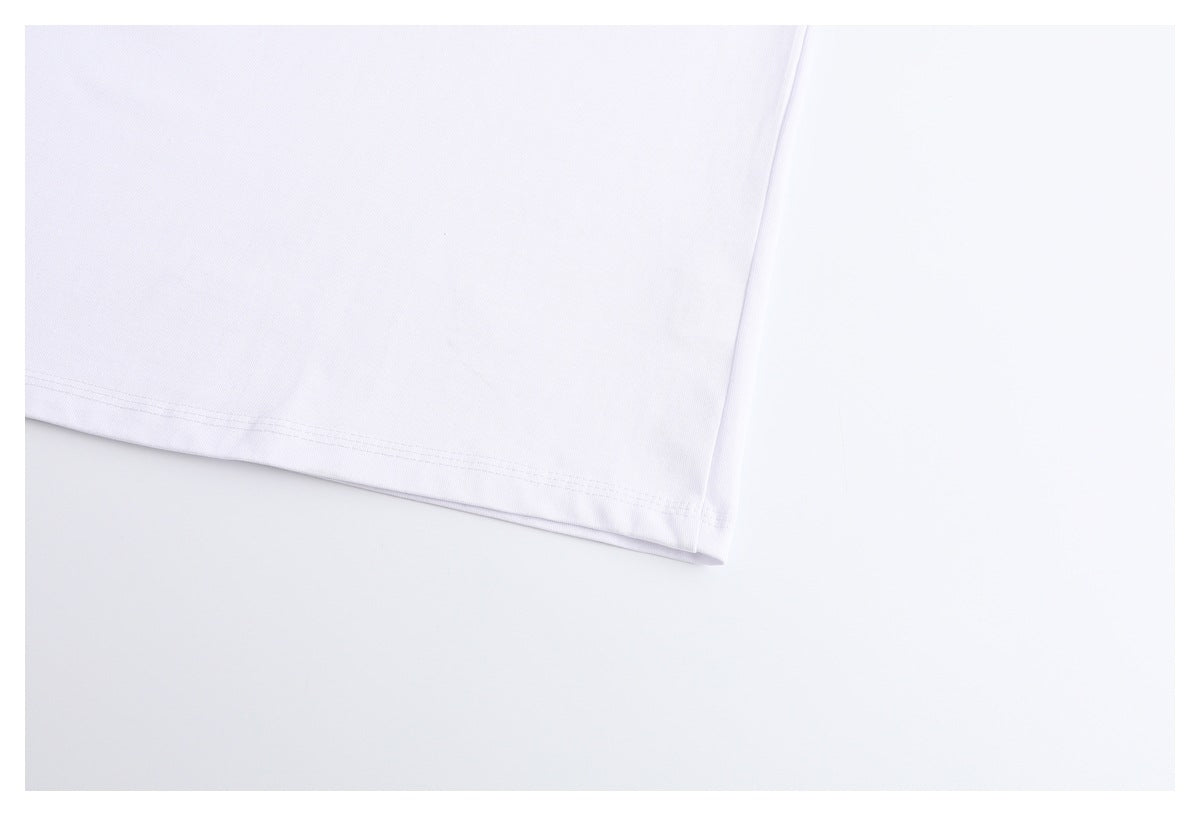 Close-up of a white garment’s stitched hem against a pale background.