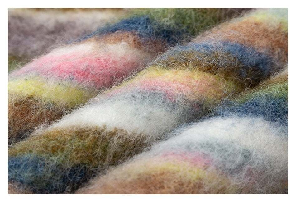 Close-up of soft fuzzy fabric folds with broad multicolor stripes in pink, yellow, cream, brown, olive, and blue.