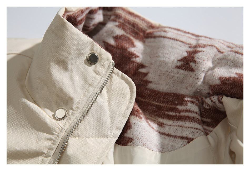 Close-up of a beige jacket's zip and snap closure with brown patterned lining visible.