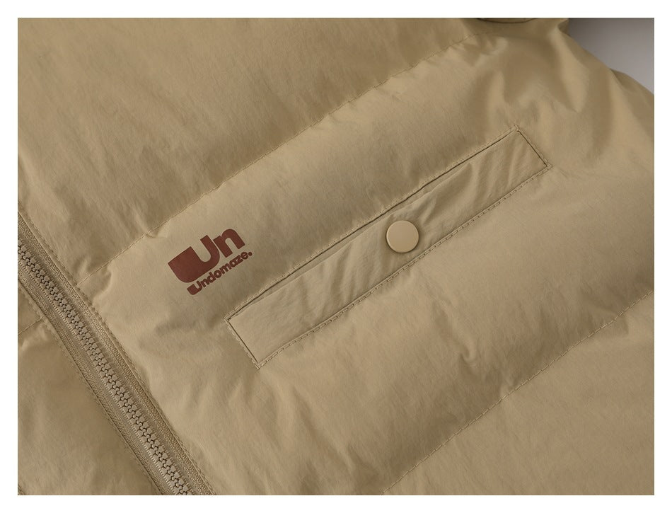 Close-up of the beige jacket's snap-pocket flap, zipper, and printed brown garment logo.