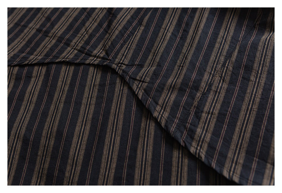 Close-up of overlapping dark shirt fabric with narrow brown vertical stripes and a stitched seam.