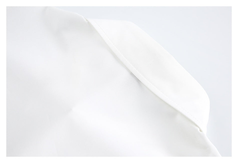 Close-up of a pointed folded edge on a white garment, with a stitched seam.