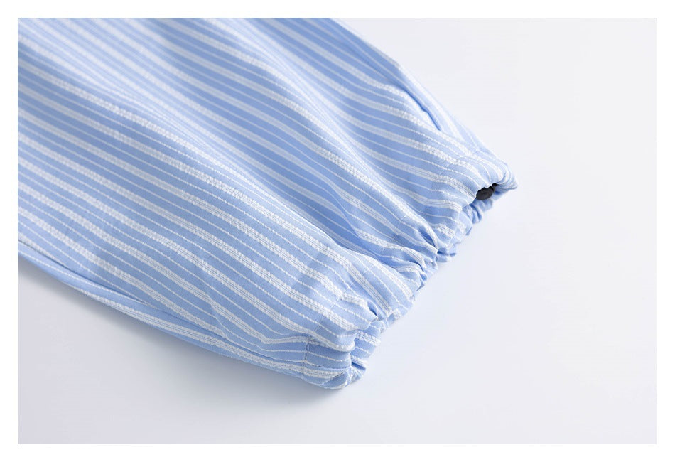Close-up of a gathered, adjustable opening on light blue shorts with narrow white stripes.