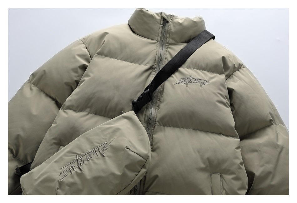 Close view of the puffer jacket's front and matching crossbody bag, showing embroidered script and black strap.