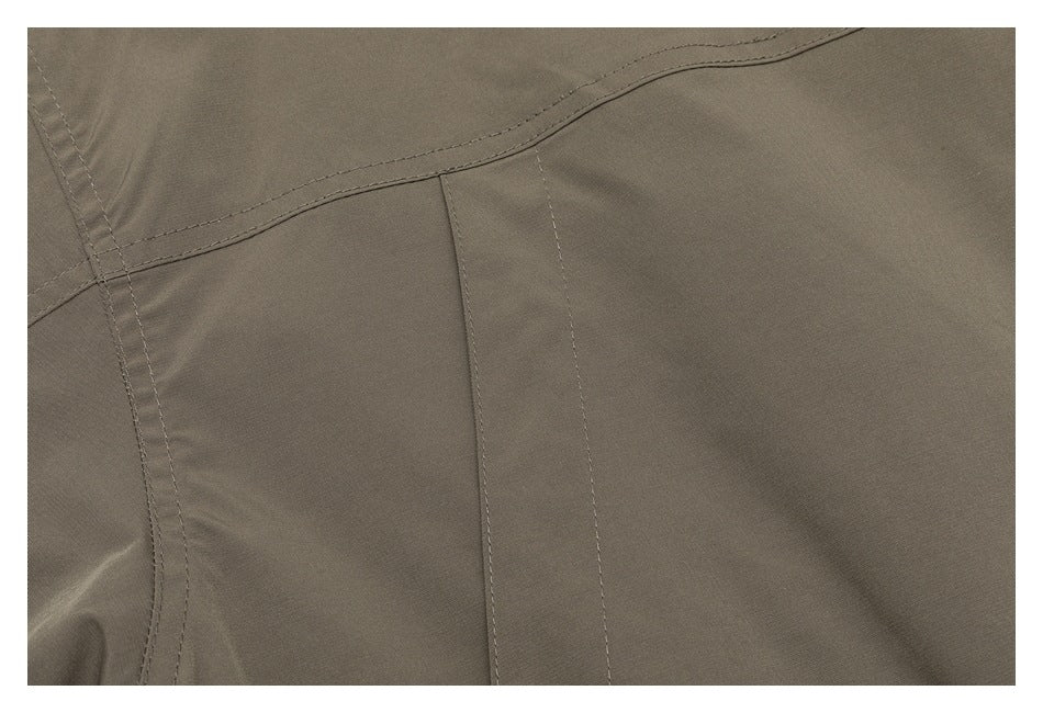 Close-up of a taupe jacket panel with a stitched pocket and curved seam.