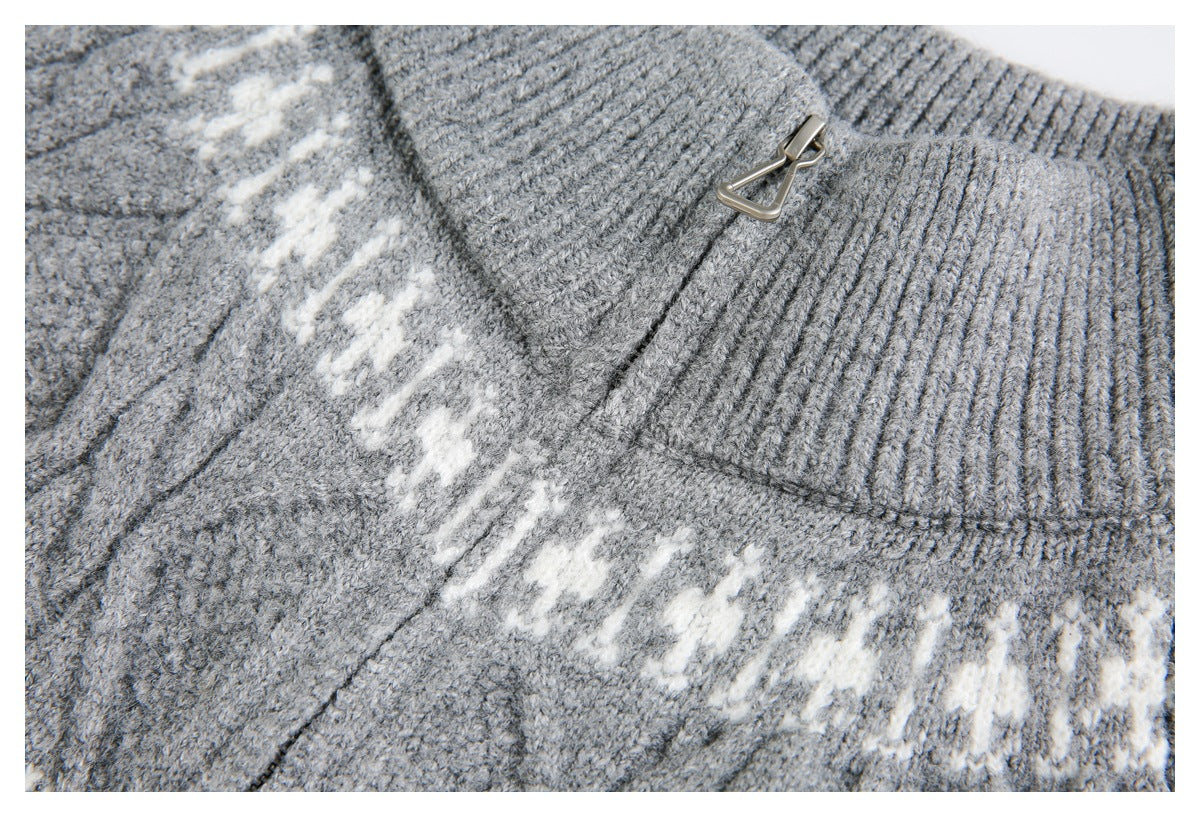 Close-up of gray ribbed knit and a small metal zipper pull beside a cream patterned band.