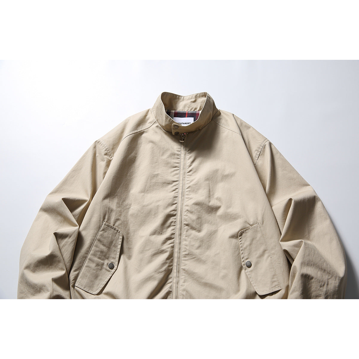 Front view of a light beige zip-front jacket with a stand collar and two flap pockets.
