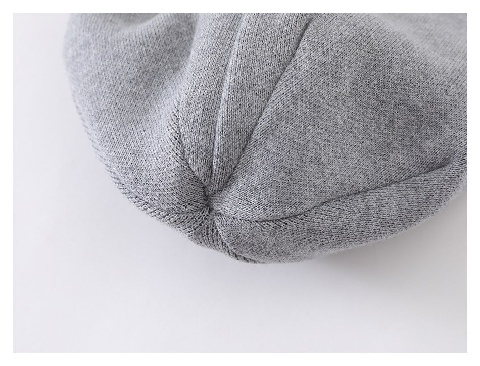 Close-up of a light gray knitted cap showing its joined crown panels and stitching.