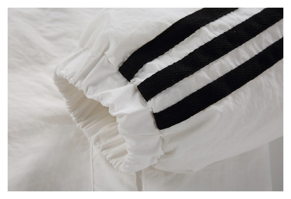 Close-up of a gathered elastic cuff with three black stripes on a white garment.