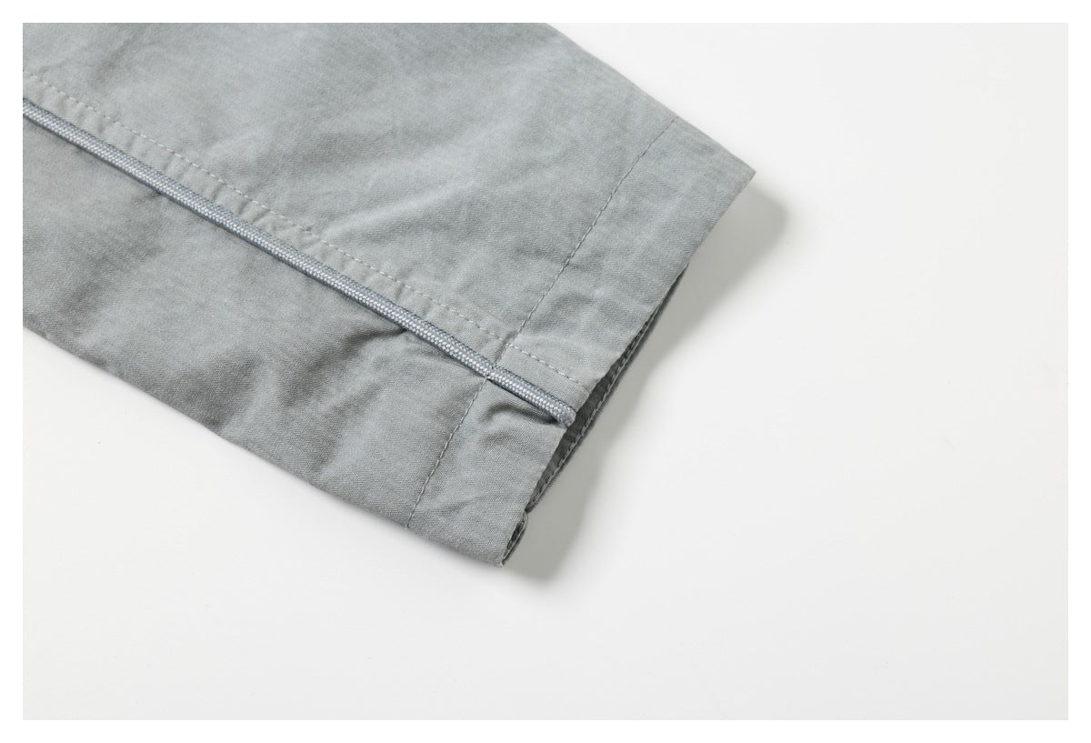 Close-up of a light gray garment edge with a narrow piped seam and stitching.