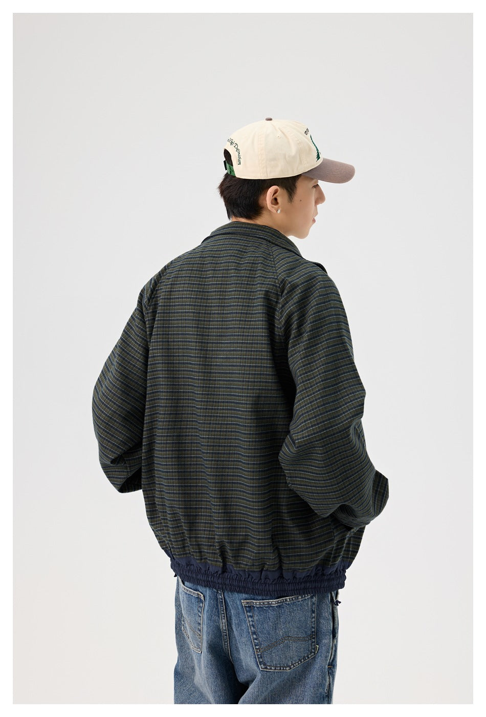 Rear view of a man wearing a dark green and navy striped jacket with a gathered navy hem.