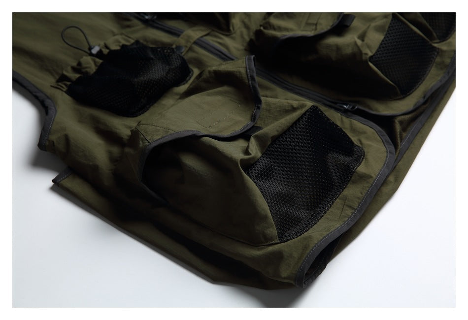 Close-up of an olive-green garment showing several black mesh pockets and dark edging.