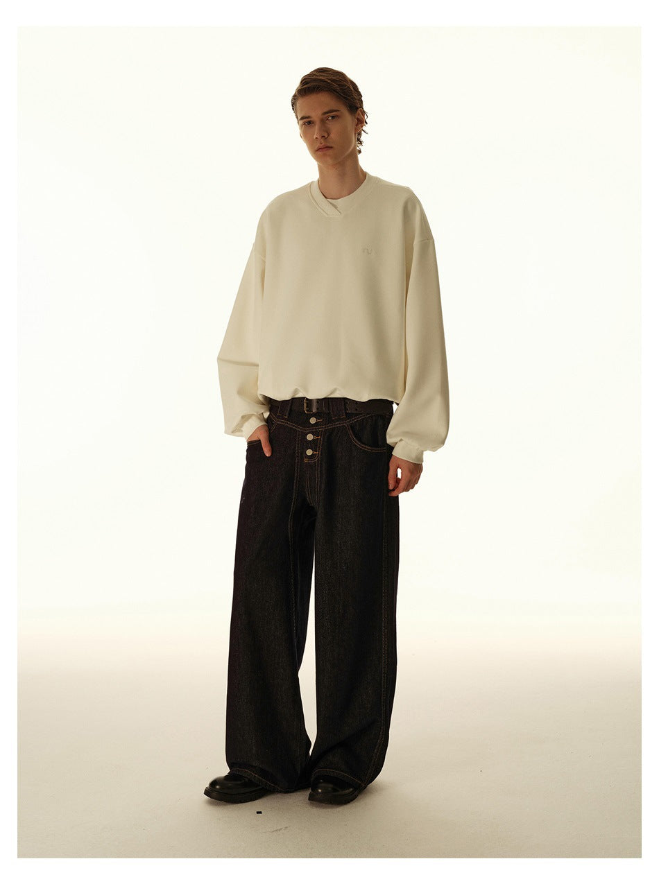Model wearing dark wide-leg button-front jeans with a cream sweatshirt, belt and black leather shoes