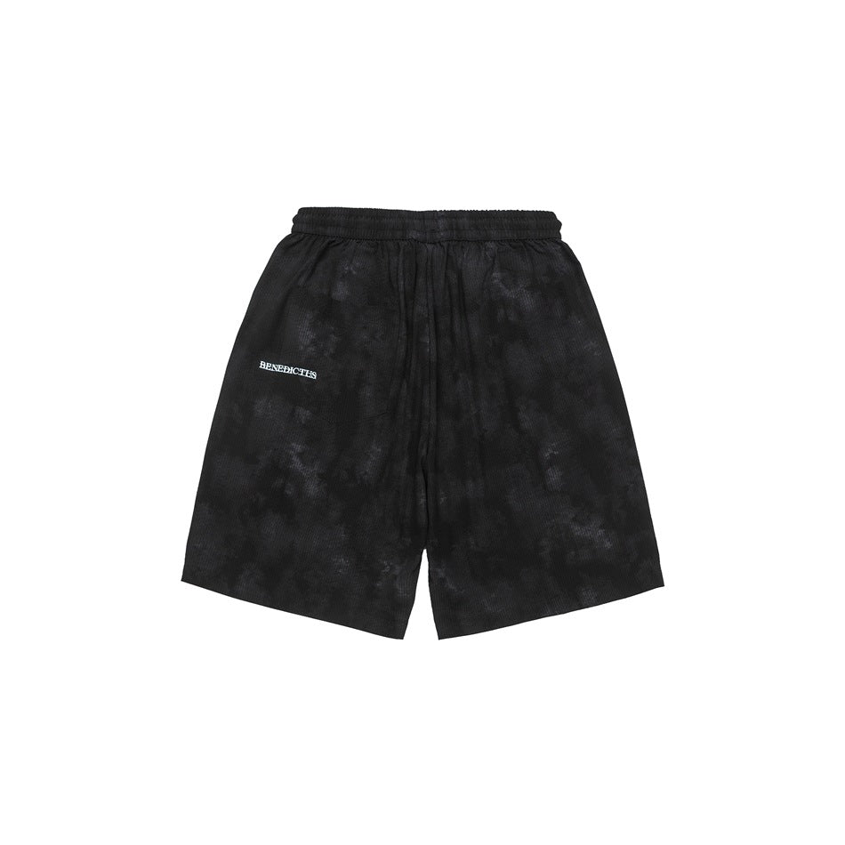 Front view of loose-fit black shorts with an elastic waistband, mottled finish, and small white thigh lettering.