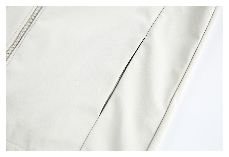 Close-up of an ivory garment panel with a curved seam and a narrow dark opening beside the edge.