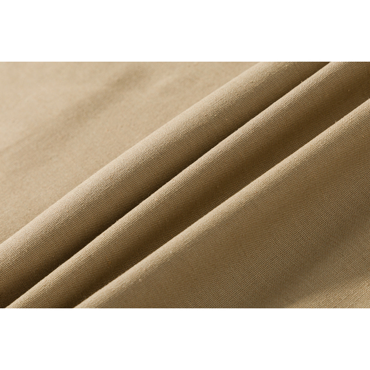 Macro view of tan fabric gathered into folds, showing its fine woven texture.