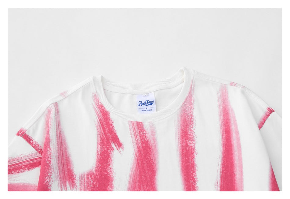 Close-up of a white crew-neck T-shirt with bold pink brushstroke graphics and a visible sewn neck label.