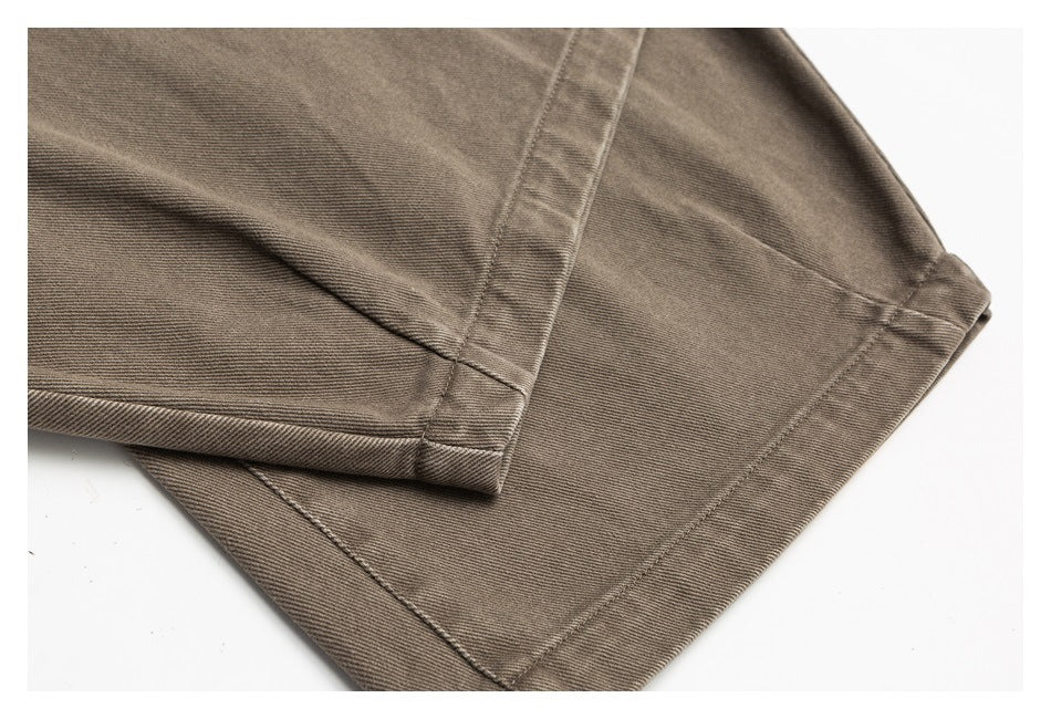 Close-up of taupe trouser leg hems, showing folded edges and stitching.