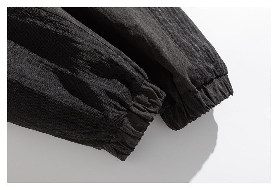 Close-up of two gathered elastic cuffs on black garment sleeves.