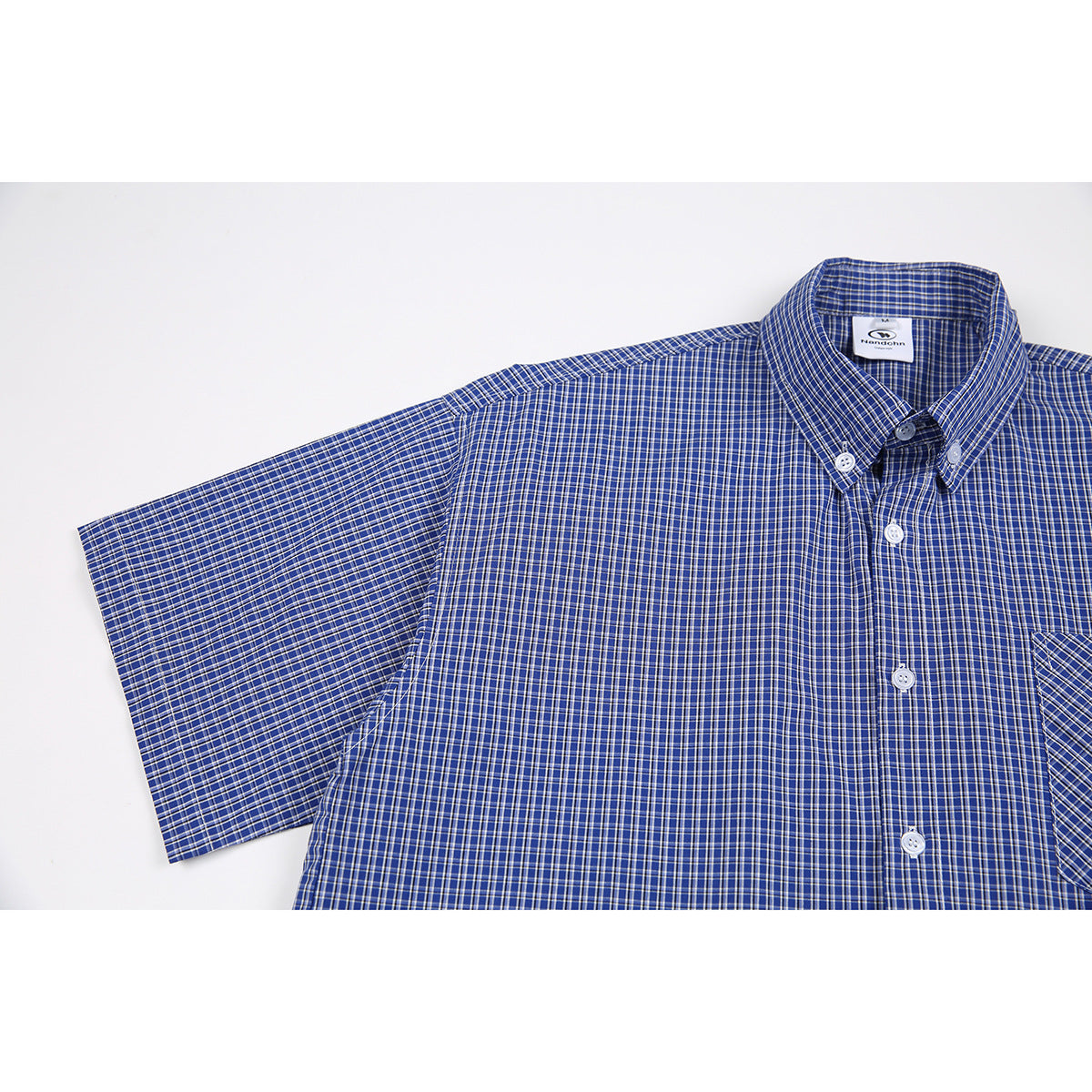 Close view of a blue short-sleeve button-down shirt with a fine white and tan check pattern.