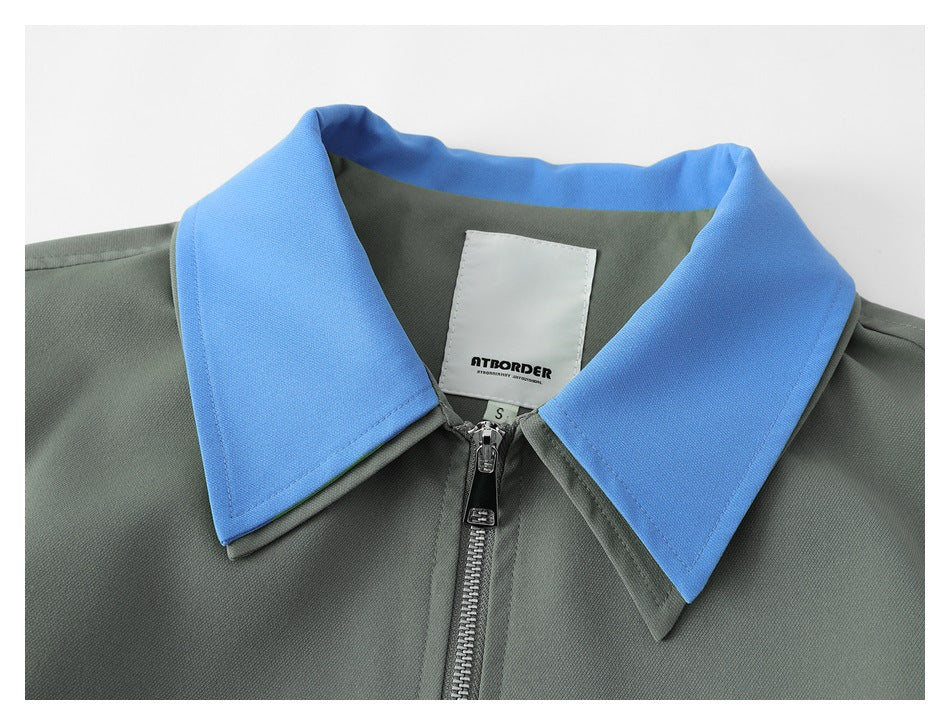 Close-up of a gray-green jacket's bright blue pointed collar, front zipper, and sewn-in neck label.
