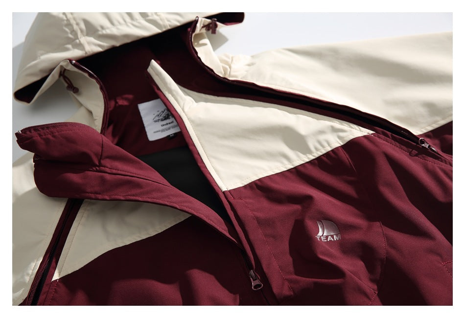 Close-up of a cream and burgundy hooded jacket with front zippers and a small TEAM emblem on the chest.