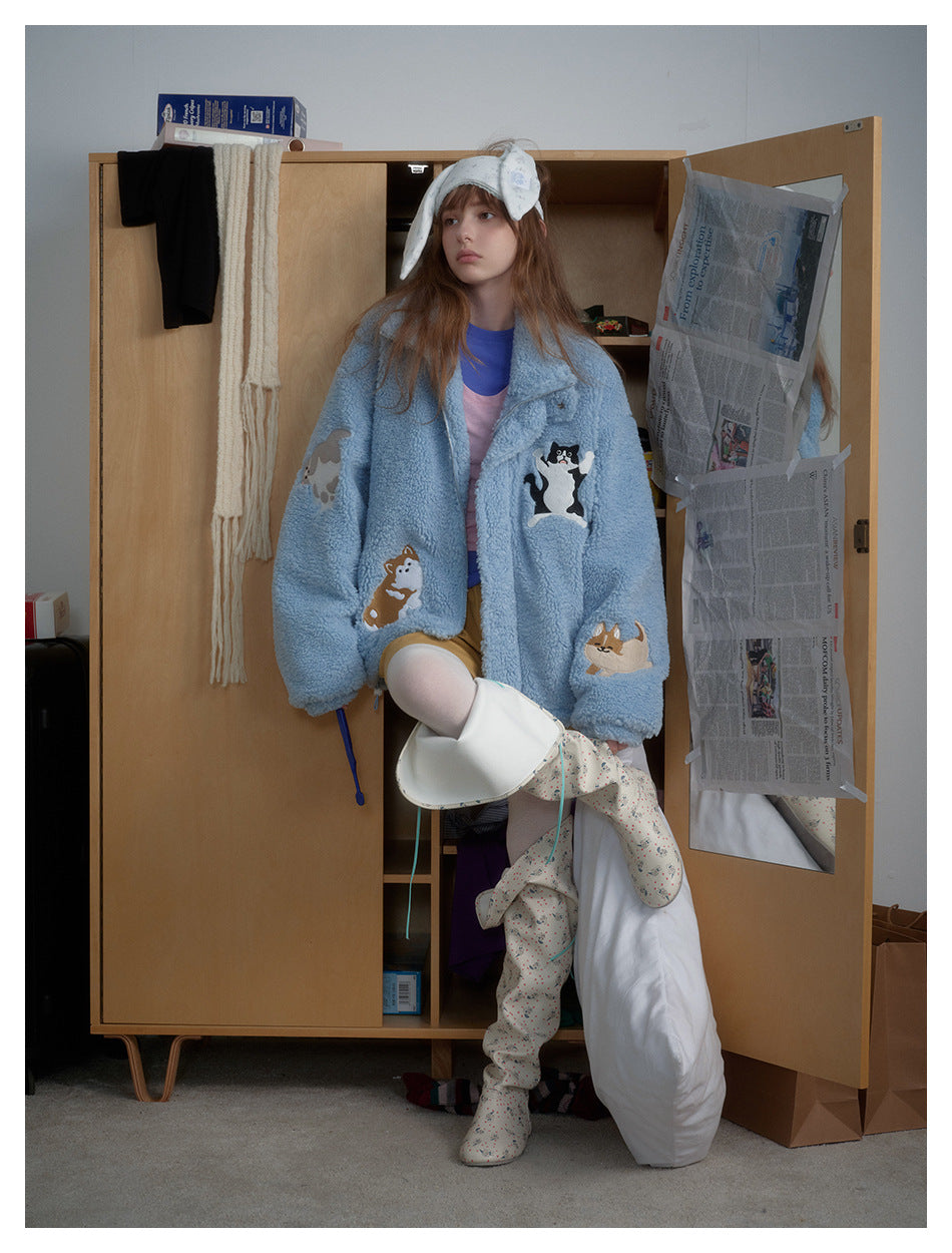 Model posed in a wardrobe wearing the light blue fleece-style jacket with embroidered cat and dog appliqués