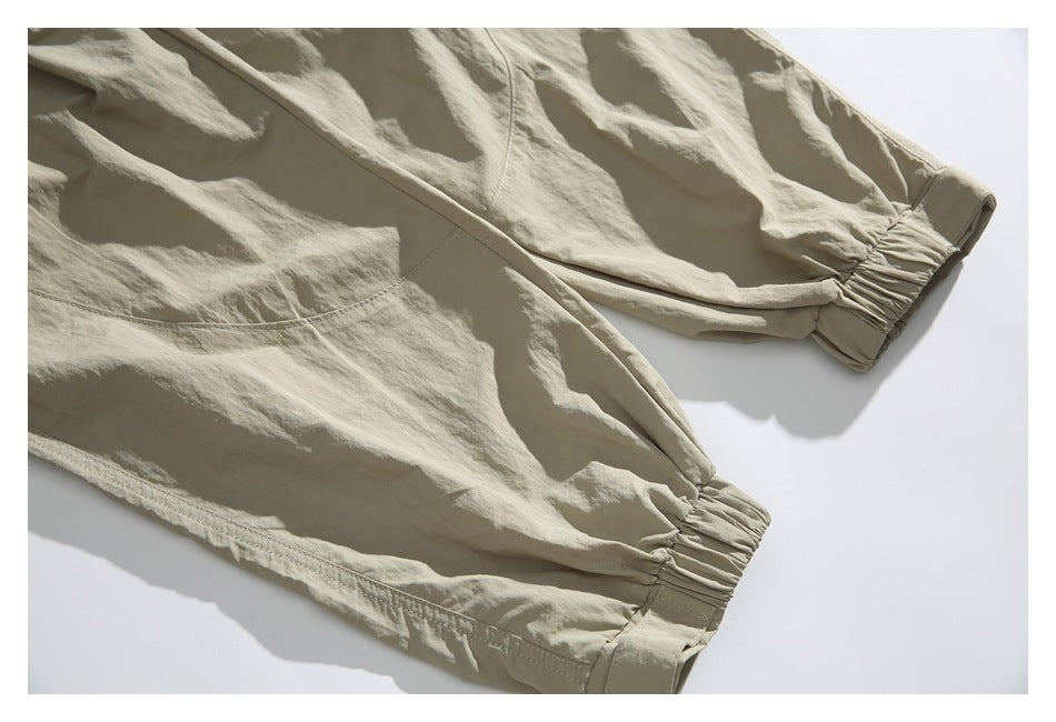 Close-up of beige trouser legs showing gathered elastic ankle cuffs and stitching.