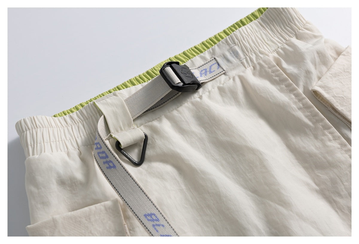 Close-up of an ivory skirt's elastic waistband, lime-green inner trim, and adjustable webbing strap with a black buckle.
