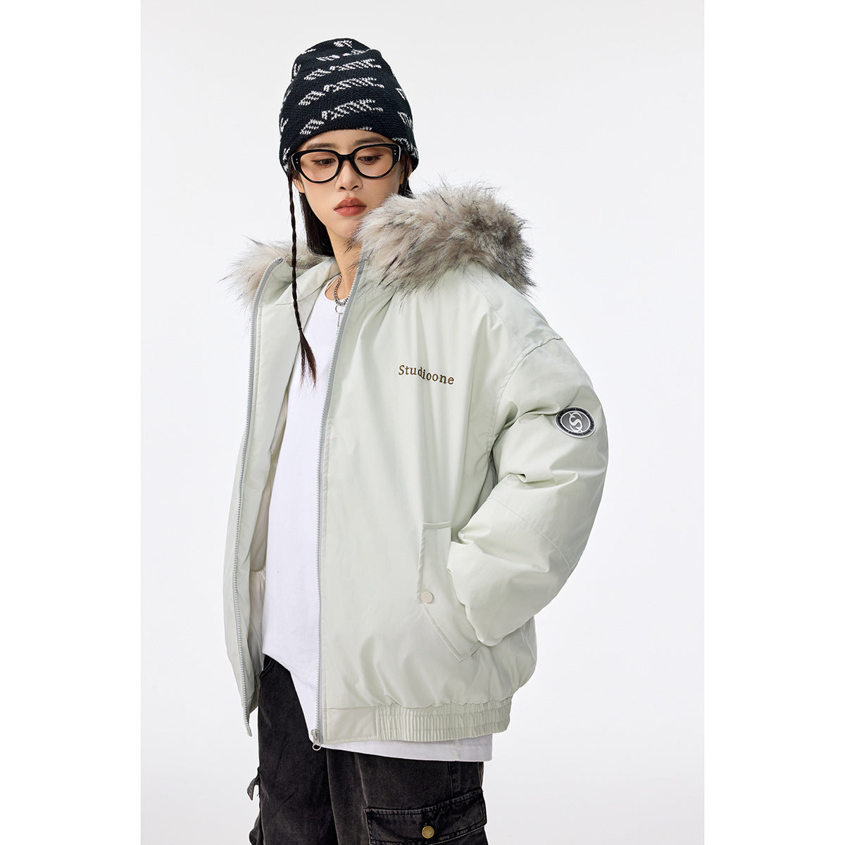 Model wearing a pale mint zip-front jacket with a gray faux-fur hood, flap pockets, and sleeve patch.