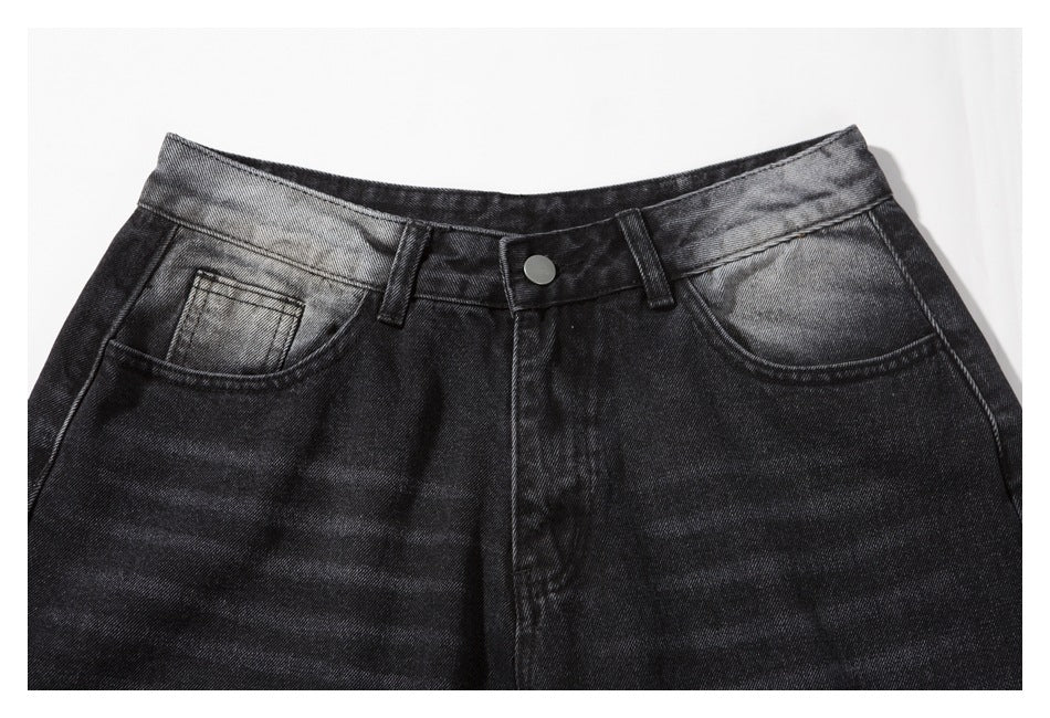 Close-up of the front waistband, button, belt loops, and pockets on faded charcoal-black denim shorts.