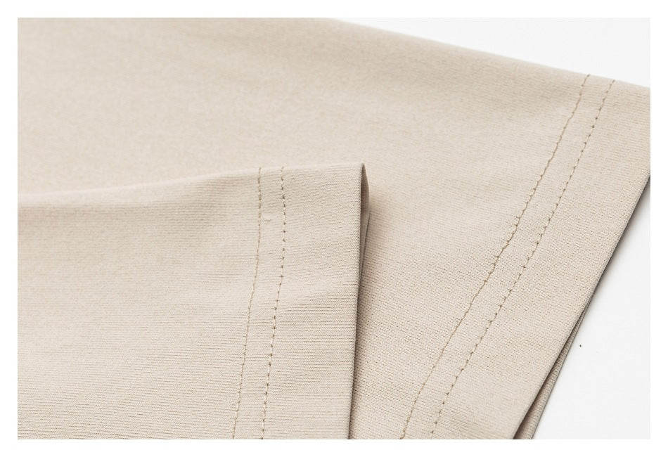Close-up of a beige garment sleeve and hem with visible double stitching.