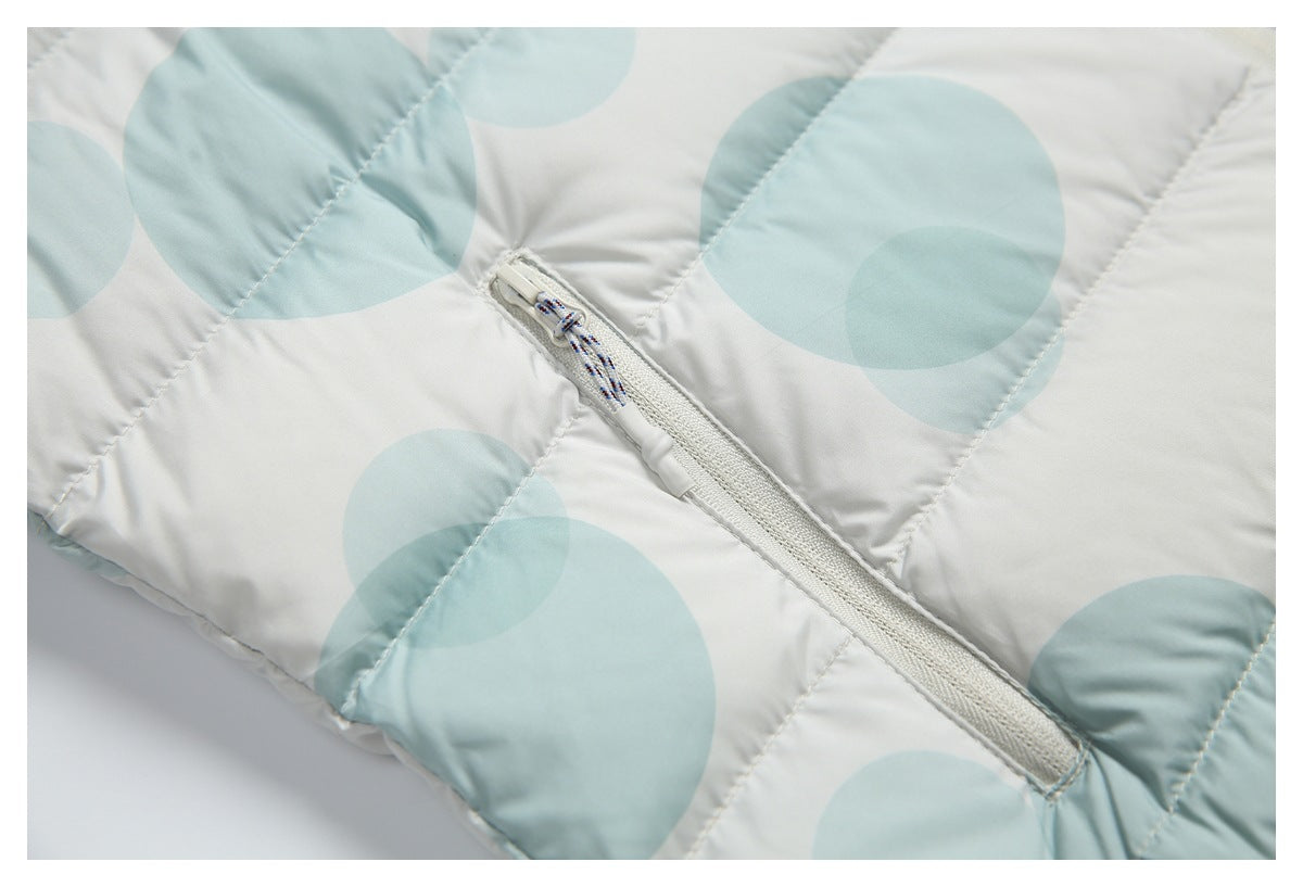 Close-up of a white zip pocket on a quilted jacket with pale aqua circles and a patterned pull cord.