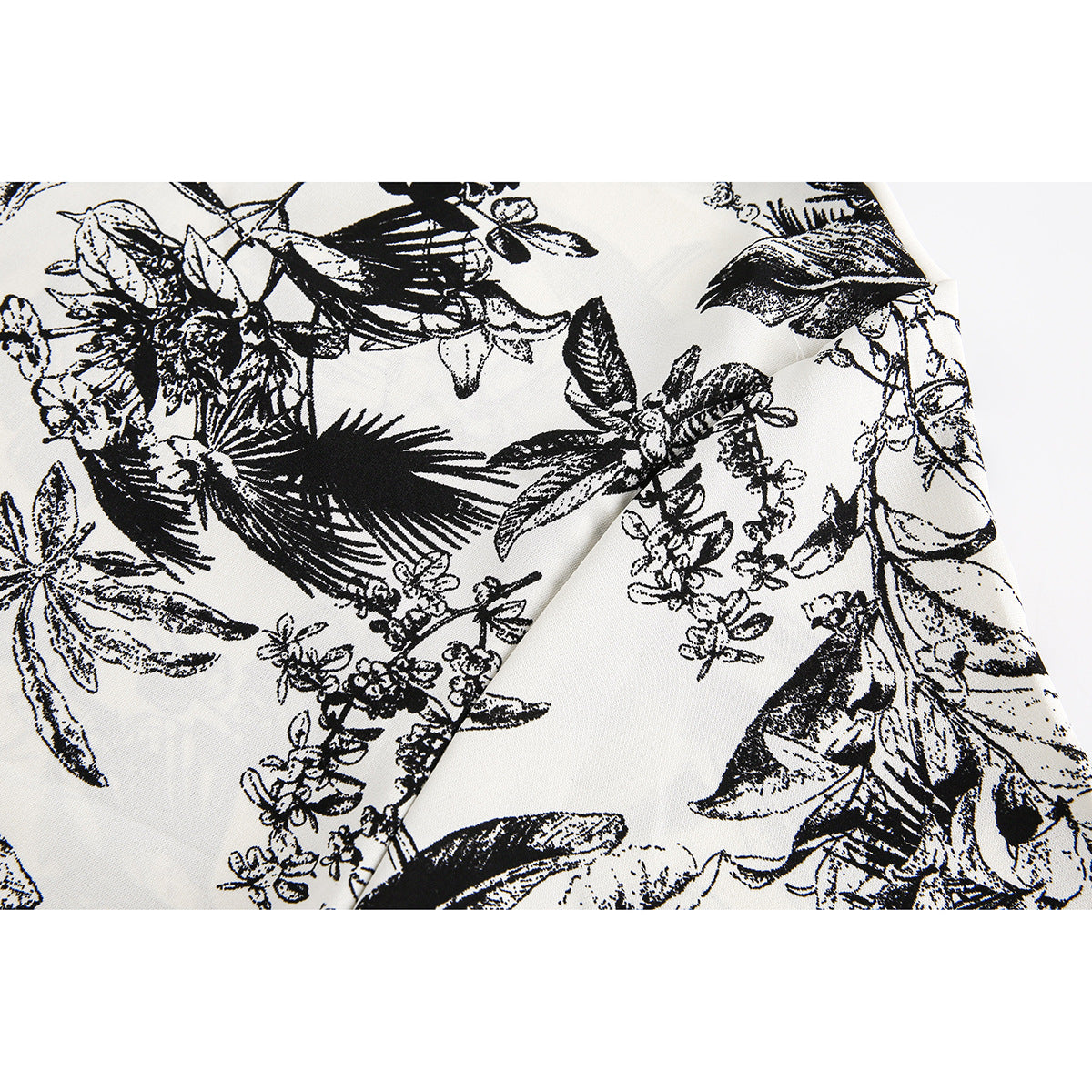 Close-up of the ivory fabric's black botanical print and a folded seam.