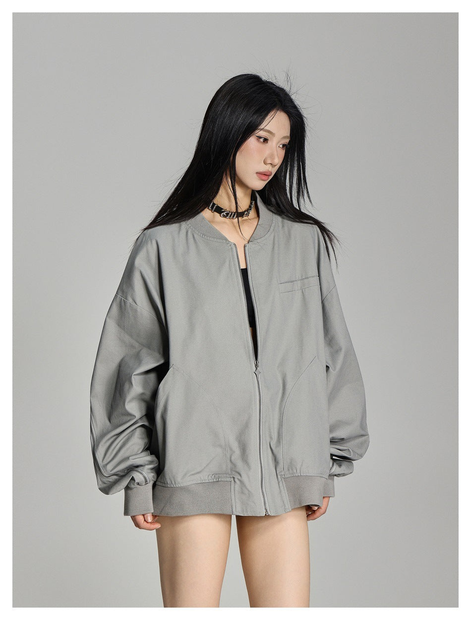 Three-quarter view of a model wearing a light gray oversized jacket, partly unzipped to show the front pockets and ribbed
