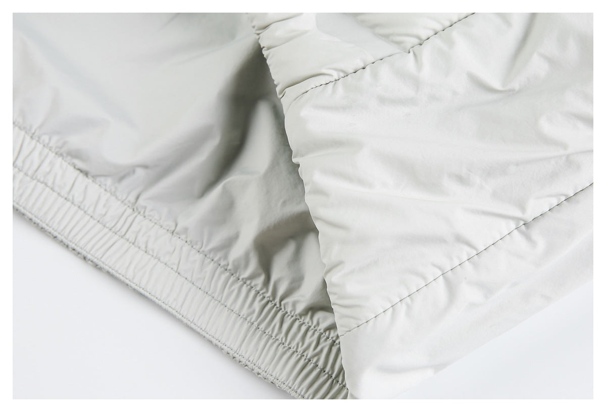 Close-up of a pale gray padded jacket showing a gathered elastic hem and stitched quilted panels.