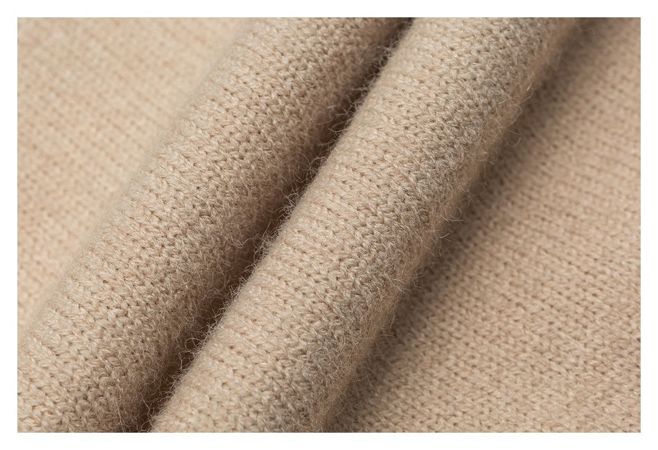 Extreme close-up showing the beige sweater's knitted texture and soft fibers.