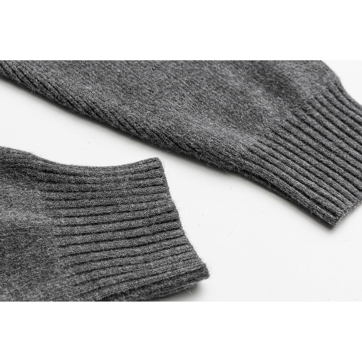Close-up of a gray knit cardigan's ribbed sleeve cuffs and textured fabric.