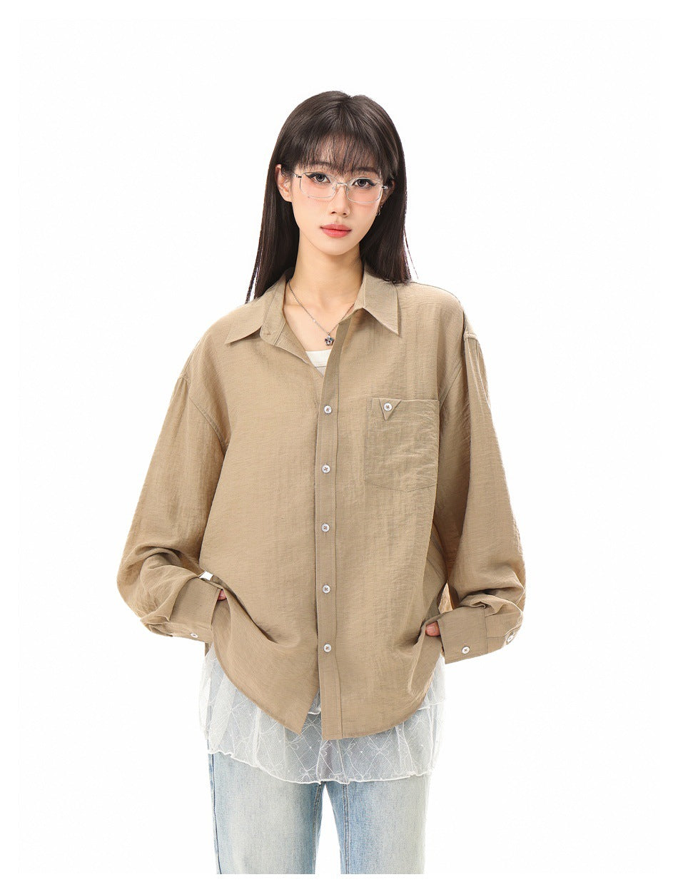 Front view of a model wearing a loose tan button-up shirt with a pointed collar, white buttons, and chest pocket.