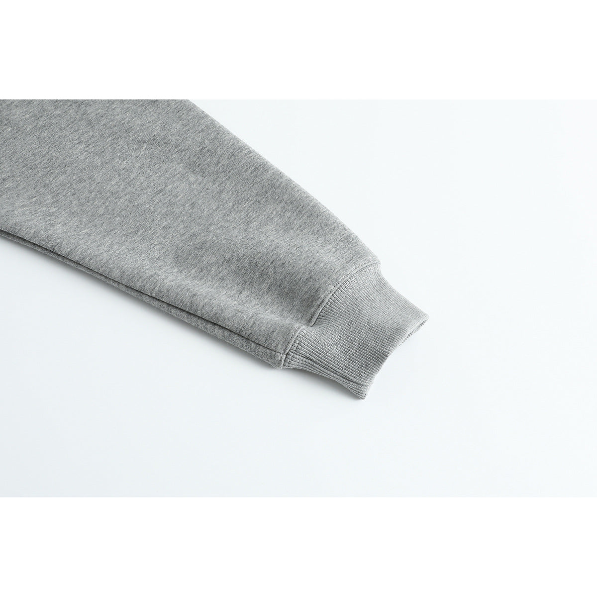 Close-up of a gray pullover sleeve ending in a ribbed cuff.