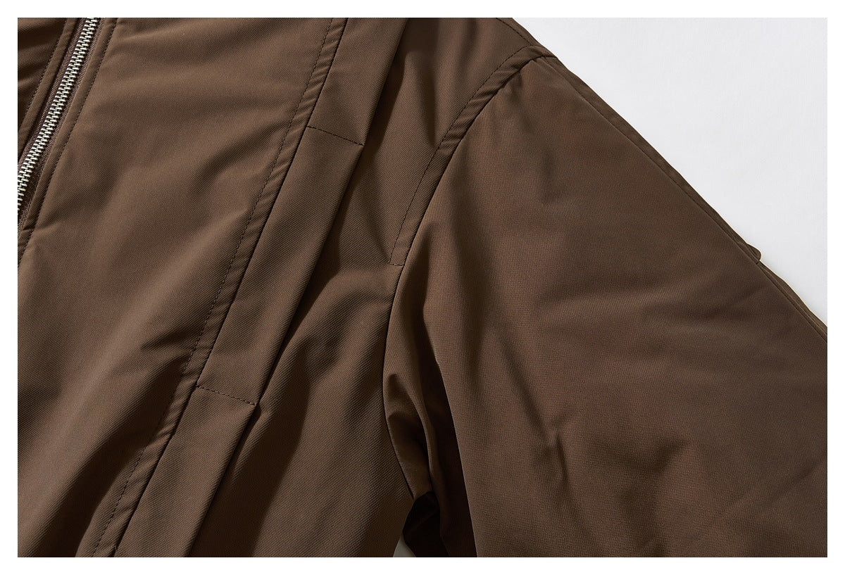 Close-up of a brown jacket sleeve and shoulder seam with part of the silver zipper visible.