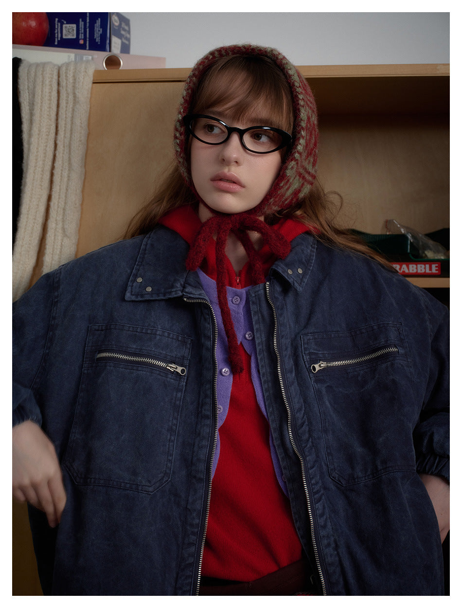 Close view of a model wearing an oversized navy washed jacket with zip chest pockets over a red top.