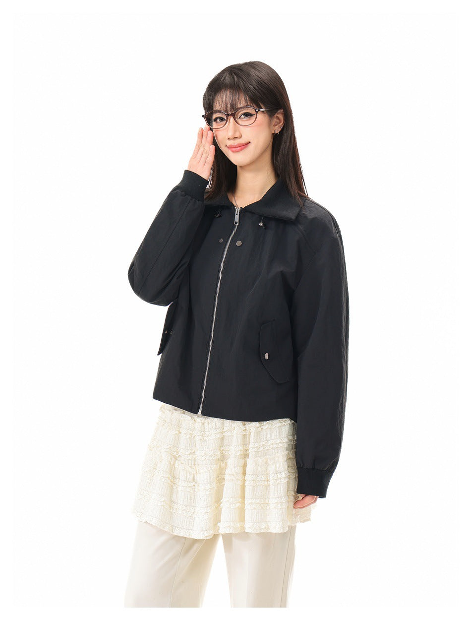 Three-quarter view of a model wearing a black collared zip jacket with flap pockets and a cream lace top.