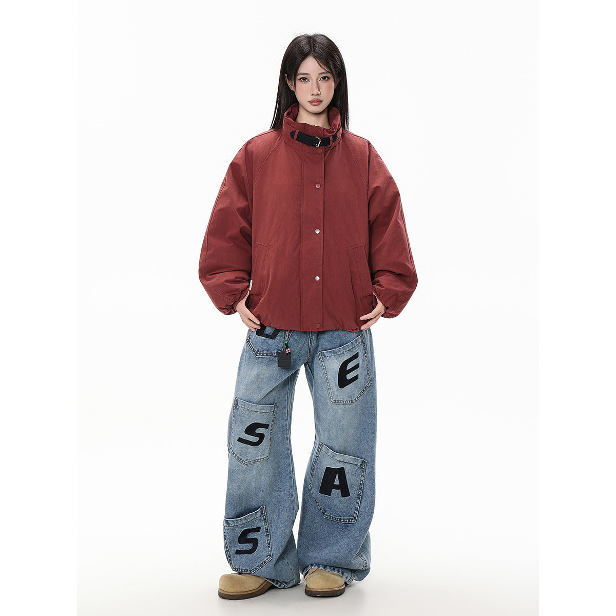 Model wearing a rust-red jacket with a high buckled collar, snap front, roomy sleeves and slanted pockets.