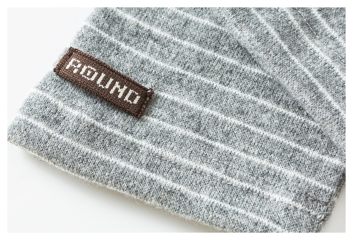 Close-up of gray knit fabric with white stripes and a small brown sewn-on label.